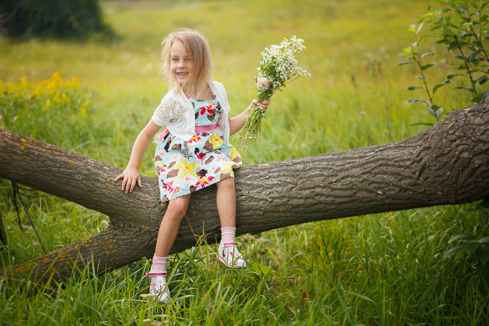 Фотосъемка девочки на дереве посреди поляны